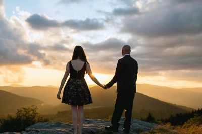 Romantic couple holding hands during a honeymoon trip at sunset in the mountains – Ghoom Bindaas Holidays